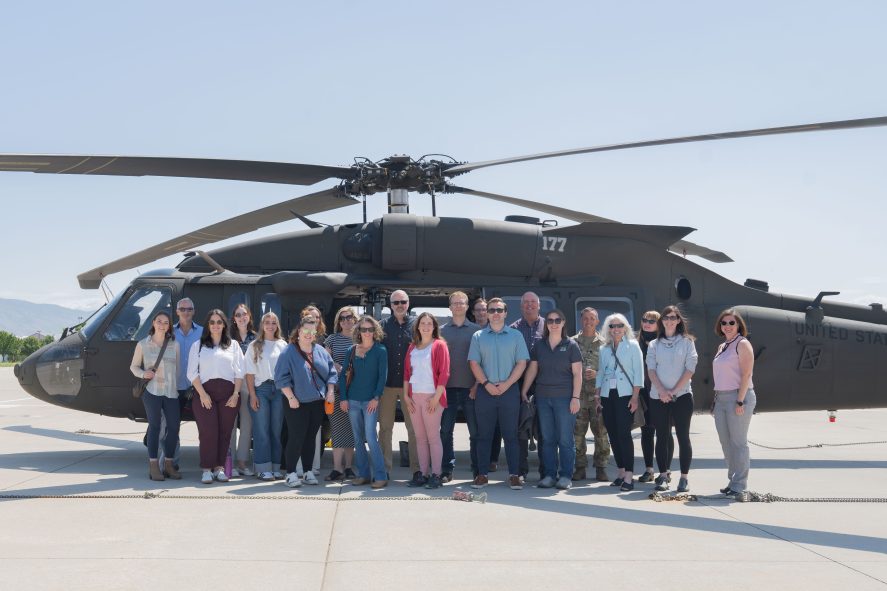 PIER team group photo in front of a military helicopter