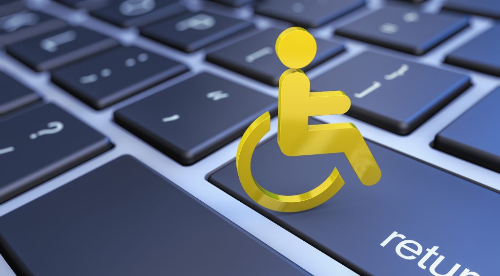 A yellow accessibility icon (person in a wheelchair) on the 'return' key of a dark, backlit computer keyboard.