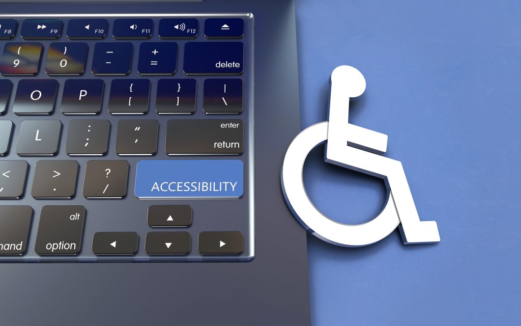 A white accessibility icon (person in a wheelchair) partially resting on a laptop keyboard next to a blue key labeled "ACCESSIBILITY".